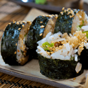 Imagen de un roll de sushi California ebi. El roll está hecho con arroz, alga nori, camarón, palta y aguacate.