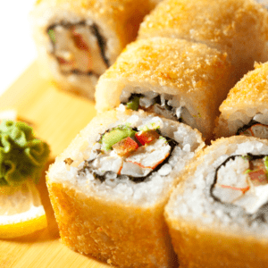 Un rollo de sushi con kanikama, queso crema y cebollín, tempura. El kanikama es blanco y crujiente, el queso crema es blanco y cremoso, el cebollín es verde y fresco, y la tempura es dorada y crujiente.