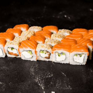 Un rollo de sushi con salmón, queso crema y palta. El salmón es rosado y brillante, el queso crema es blanco y cremoso, y la palta es verde y cremosa.