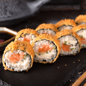 Un rollo de sushi con salmón, queso crema y cebollín, tempura. El salmón es rosado y brillante, el queso crema es blanco y cremoso, el cebollín es verde y fresco, y la tempura es dorada y crujiente.