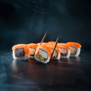 Un rollo de sushi con salmón, queso crema y cebollín. El salmón es rosado y brillante, el queso crema es blanco y cremoso, el cebollín es verde y fresco, y la tempura de gambas es dorada y crujiente.