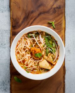 Sopa Fu Min, un delicioso plato tradicional cantonés, ahora en tu casa. Una sopa caliente y reconfortante, hecha con fideos de arroz, camarones, pollo, verduras y un caldo de sabor intenso.